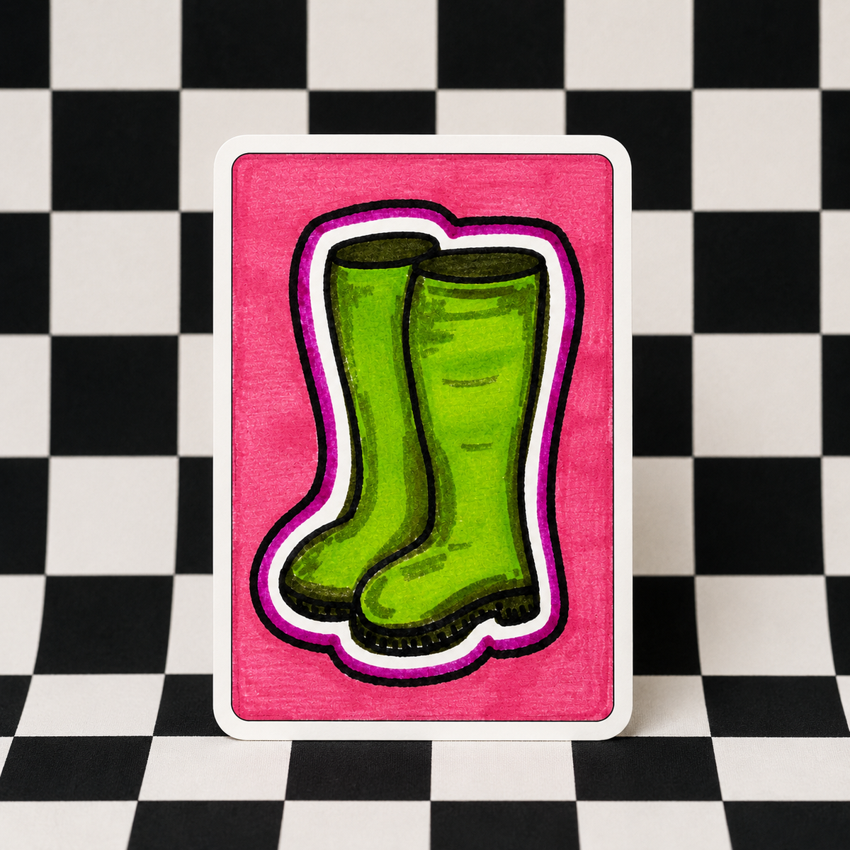 A square art print or card featuring a hand-drawn illustration of green rain boots on a bright pink background, displayed against a black and white checkered floor.